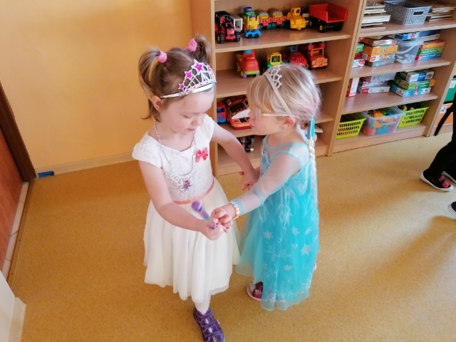 dwie dziewczynki, w strojach balowych trzymają się za ręce