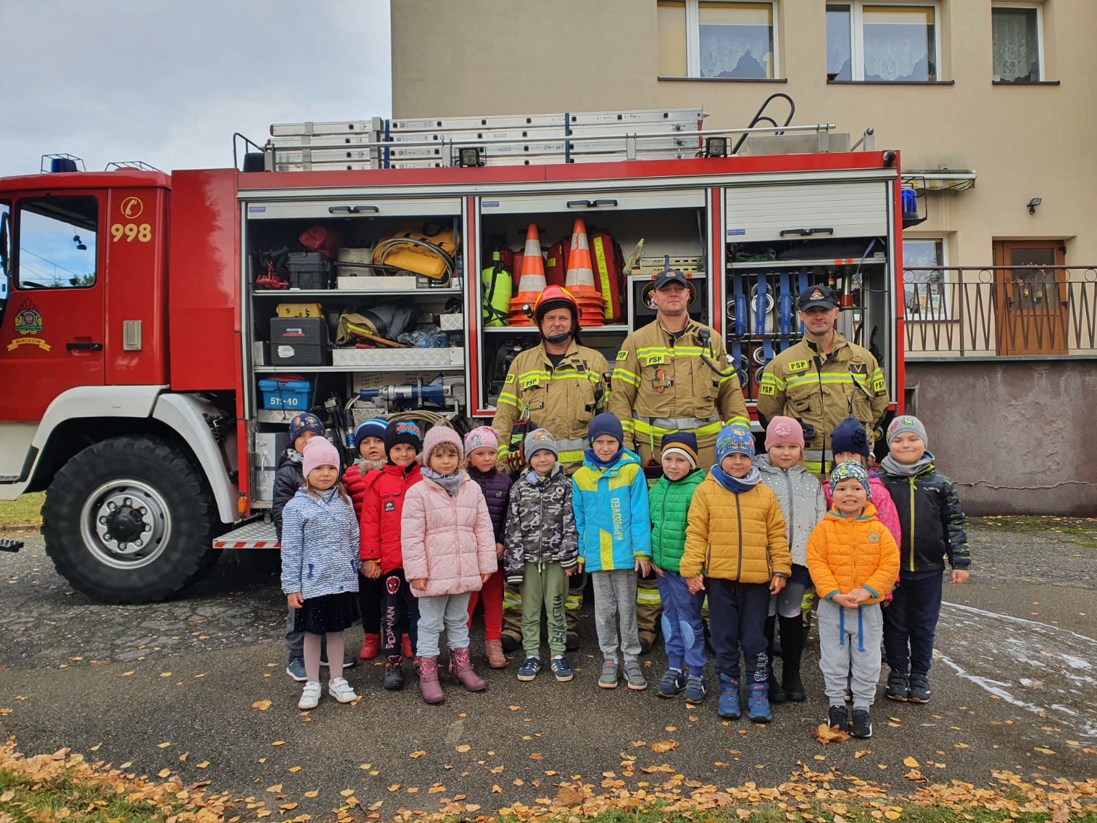 grupa dzieci wraz ze strażakami na tle wozu strażackiego