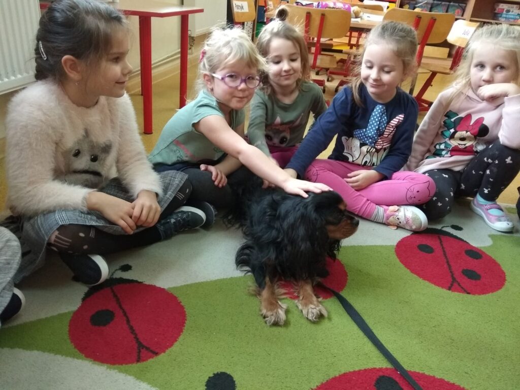grupa dzieci głaszcze psa